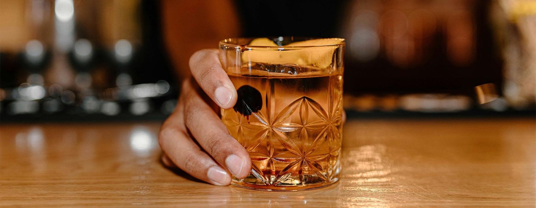 a hand holding holding a cocktail glass