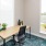 a room with a desk and chairs and window